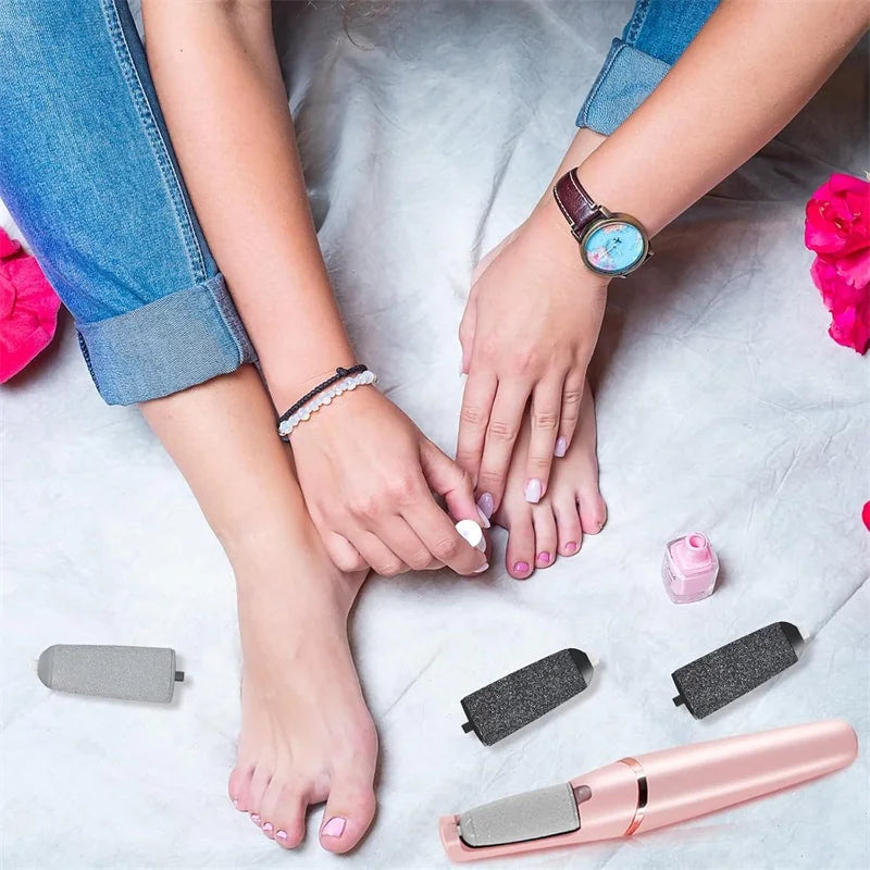 Woman performing a pedicure using pink Rolli™ SmoothPro electric foot grinder, with replacement roller heads nearby – demonstrating effective callus and dead skin removal at home